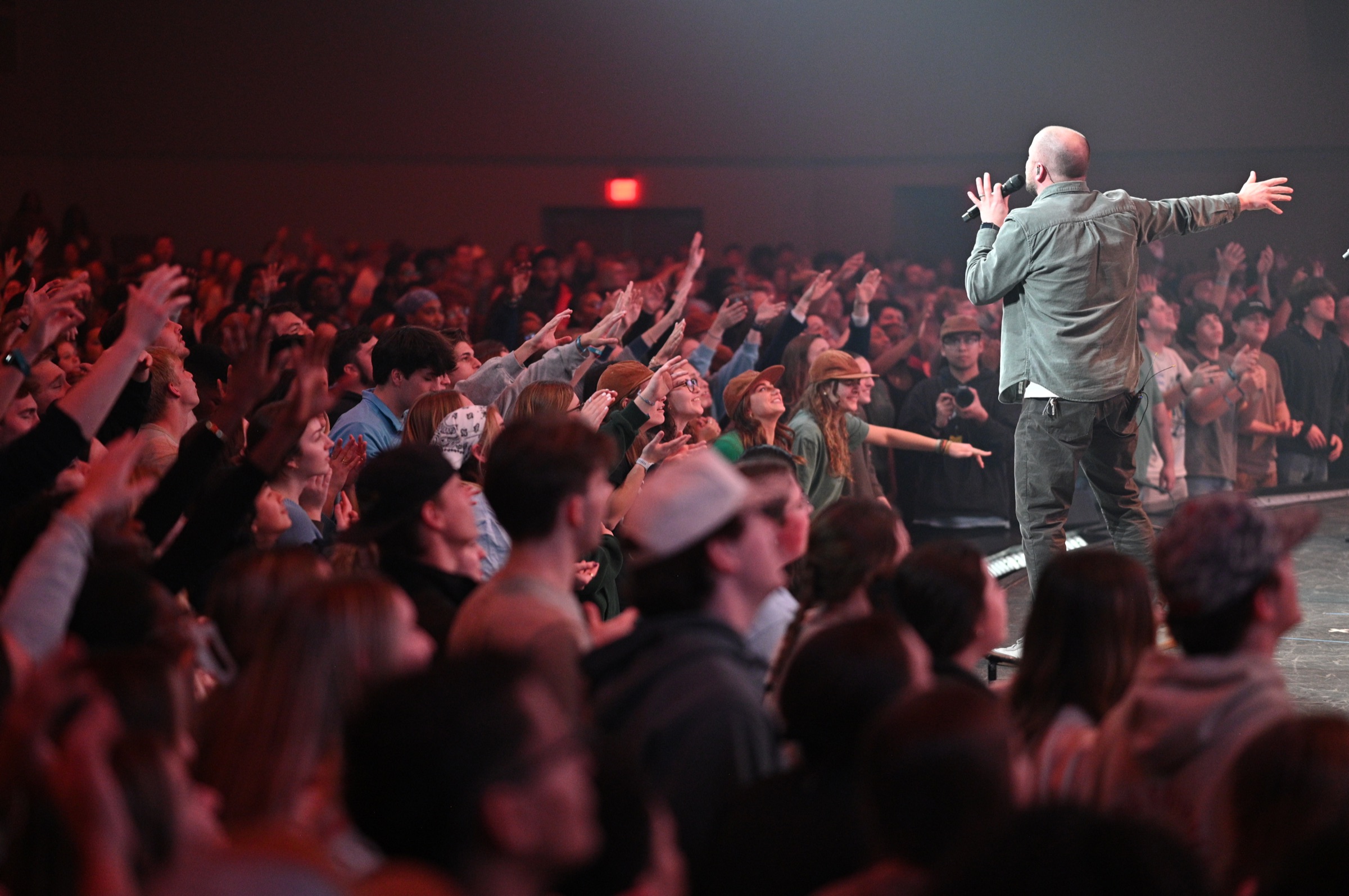 A pastor leading worship before a crowd with raised hands